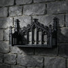 A black ornate Gothic wall shelf with intricate carvings mounted on a dark stone wall.