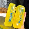 A bright yellow butter squeeze toy is held in a hand against a dark background.