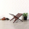 Handcrafted wooden Quran book stand with intricate arabesque design placed on a light wood surface.