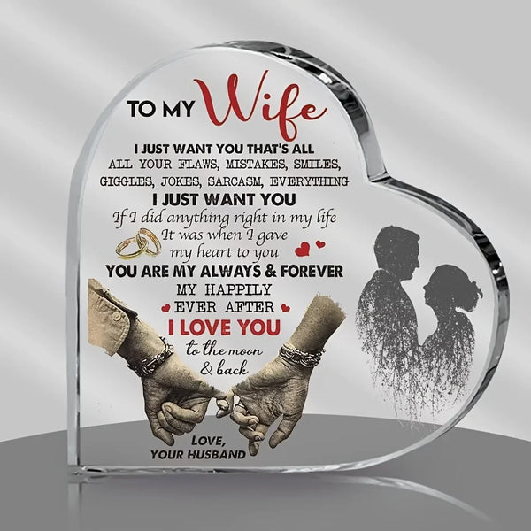 A clear heart-shaped acrylic decoration featuring text about love and a silhouette of a couple's hands.