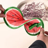 A hand is holding a foldable hand fan shaped like a sliced watermelon, green and red.