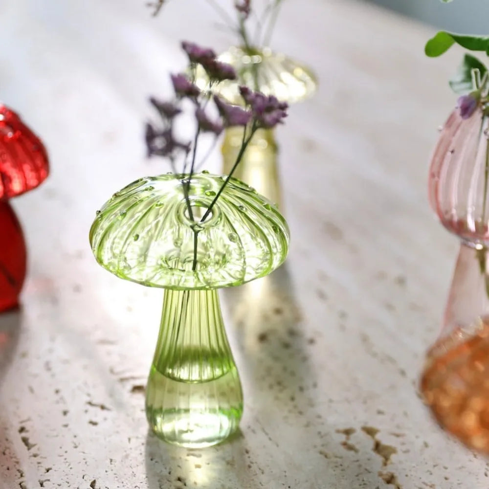 A glass vase shaped like a mushroom with translucent green jelly colors, set on a light surface.
