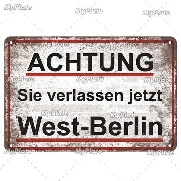 A vintage metal tin sign with a distressed gray background and red text that reads ACHTUNG Sie verlassen jetzt West-Berlin