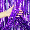 A hand is holding purple metallic foil fringe fabric against a vibrant purple curtain background.