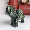 A dark green jade elephant carving statue resting on a white surface.