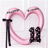 Pink heart-shaped balloon decoration with Happy Birthday text and black ribbon and number 1