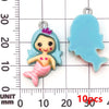 A light blue resin mermaid princess charm and a corresponding mermaid tail charm are shown against a millimeter ruler.