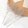 A delicate arrangement of pearl string beads is displayed on a cork board next to white lace fabric.