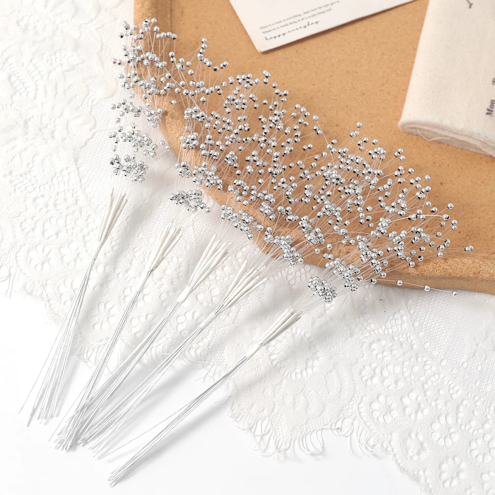 A delicate arrangement of pearl string beads is displayed on a cork board next to white lace fabric.