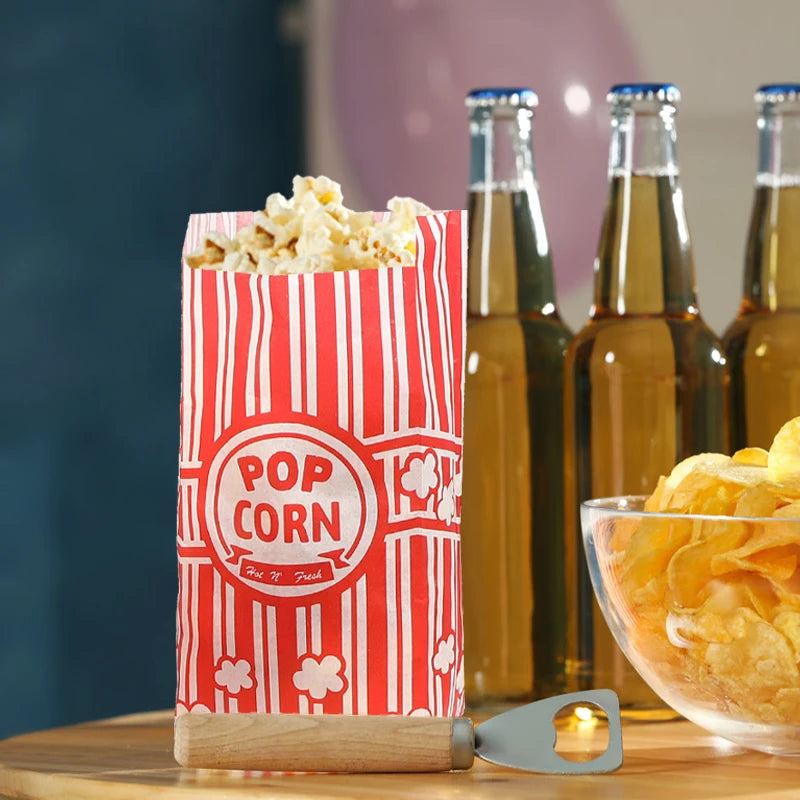 A red and white striped popcorn bucket is shown next to glass bottles of oil, with loose popcorn visible.