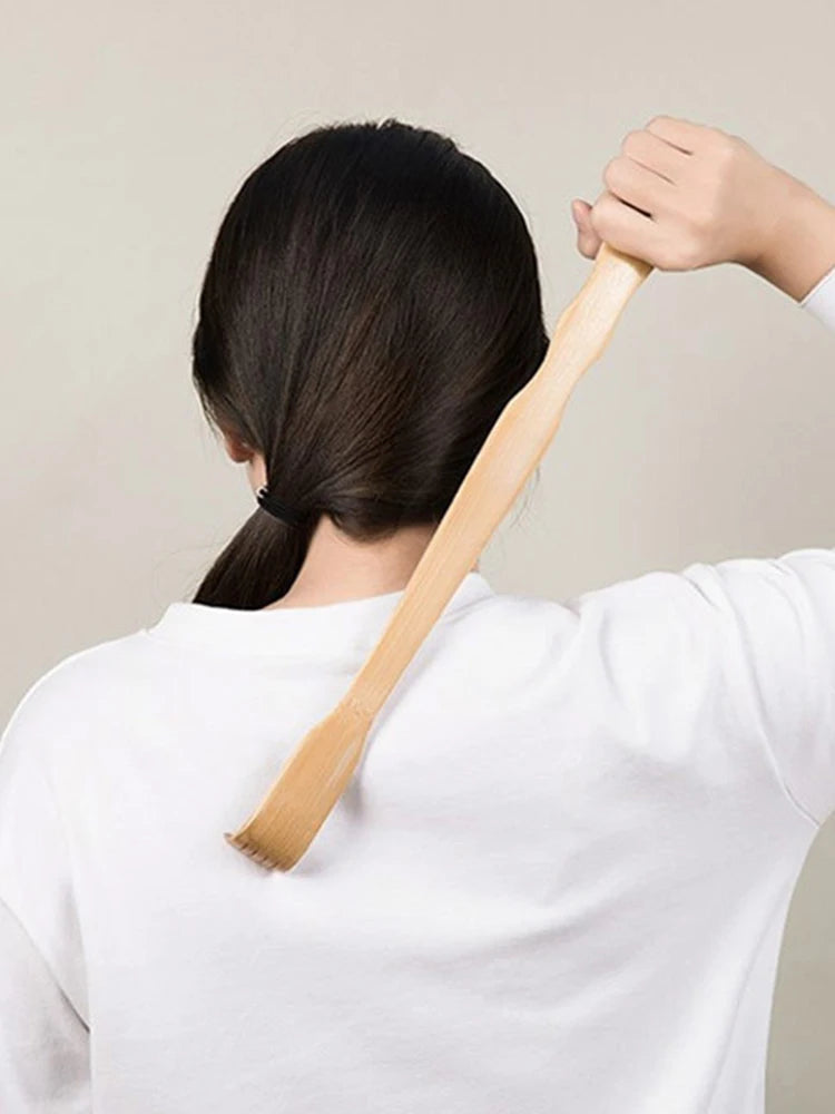 A person is using a bamboo back scratcher with a roller massager on their back.