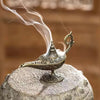 Plaque d'encens en métal de style antique avec de la fumée s'élevant sur une surface de pierre