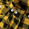 A close-up of a men's brushed flannel shirt with a yellow and black plaid pattern.