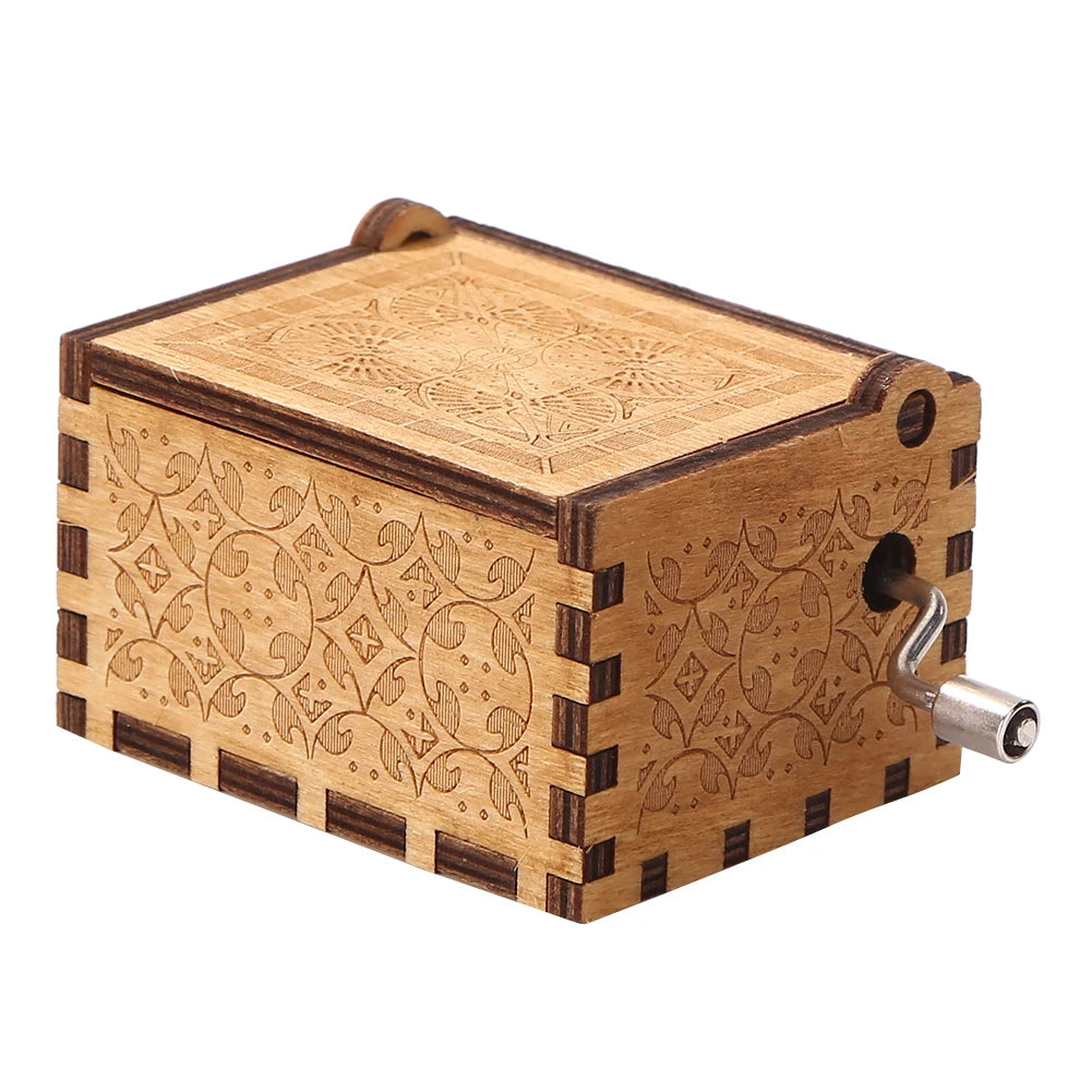 A vintage hand crank music box made of light brown wood with intricate carved patterns.