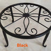 Black decorative metal plant stand with a circular wrought iron pattern.