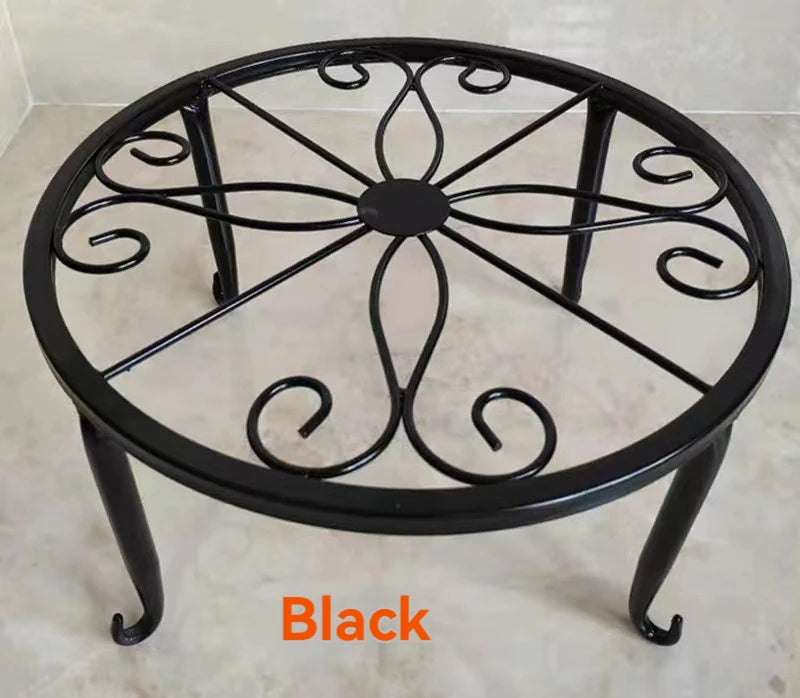 Black decorative metal plant stand with a circular wrought iron pattern.