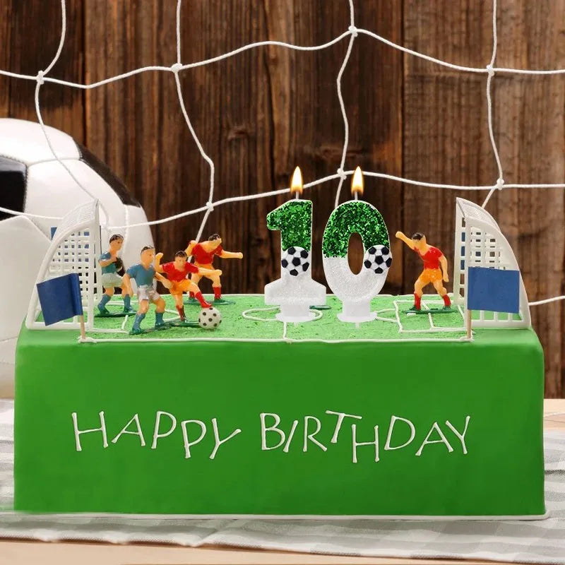 A green cake decorated with a soccer field theme featuring figurines, candles shaped like numbers, and the words Happy Birthd