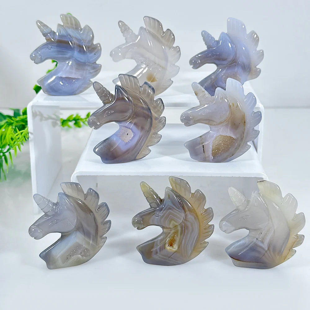 A set of natural agate crystal figurines in various shades of translucent gray and purple, displayed on a white surface.