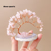 A delicate rose quartz crystal tree with pink blossoms stands on a translucent agate base.
