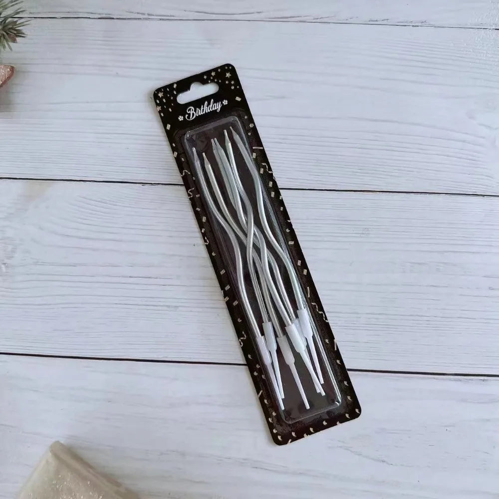 A package of long thin birthday candles with spiral tips displayed on a white wooden surface.