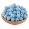 A pile of light blue textured resin beads for jewelry making in a wooden bowl.