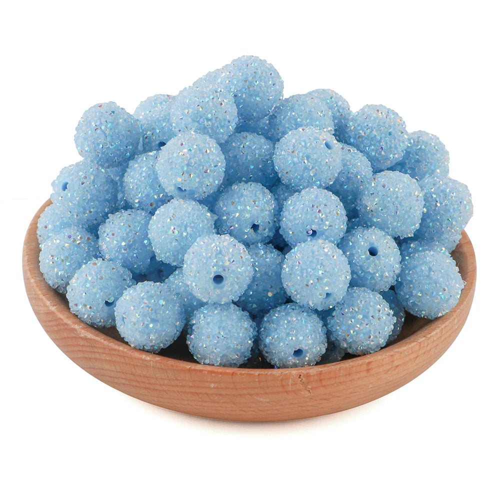 A pile of light blue textured resin beads for jewelry making in a wooden bowl.