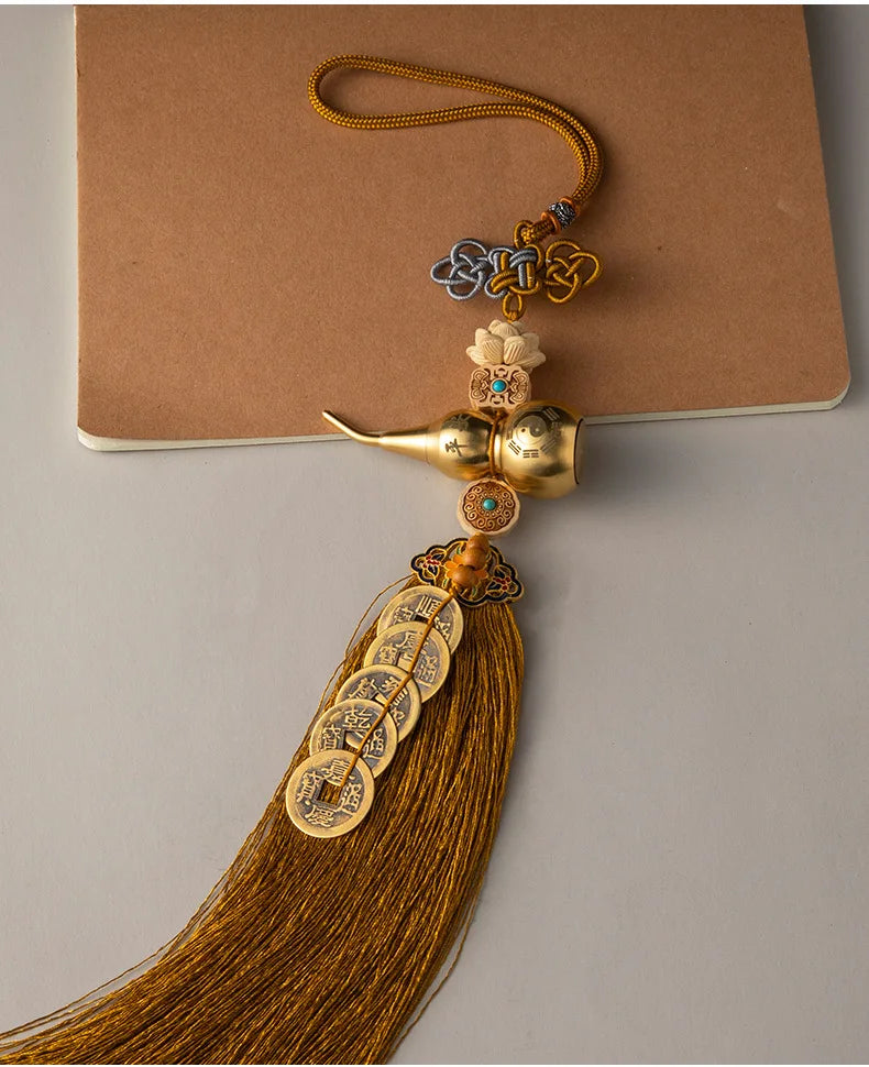 Brass gourd and five emperor coins hanging ornament with a gold tassel on a brown card.