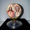 A round ornament featuring a depiction of Jesus and the Virgin Mary with halos and floral decorations.