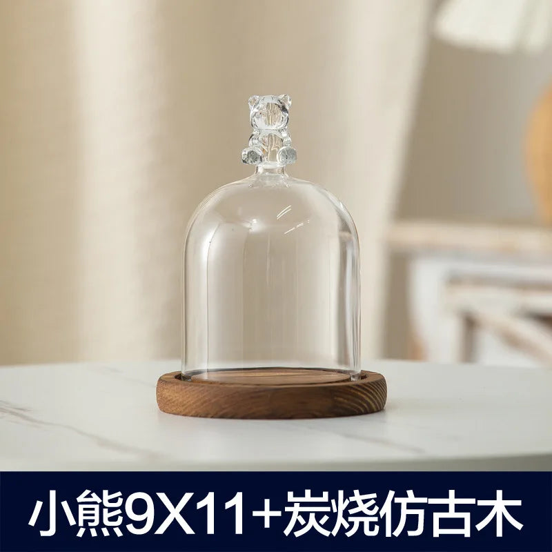 Clear glass aromatherapy candle holder with a decorative top and a wooden base.
