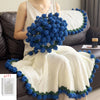 A woman models a handmade rose bouquet blanket gift featuring white knit fabric trimmed with blue and green floral accents.