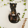 A black cat silhouette with a crescent moon design holds various crystals and glass bottles on a floating shelf.