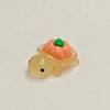 A small resin charm shaped like an orange fruit turtle with a green top and a yellow body.