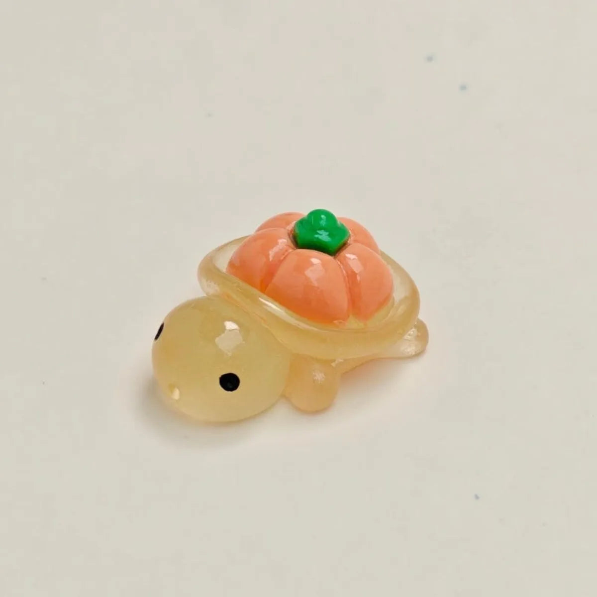 A small resin charm shaped like an orange fruit turtle with a green top and a yellow body.