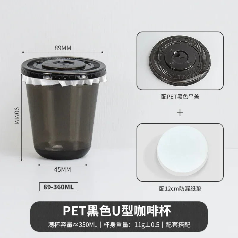 A black disposable U-shaped coffee cup with a lid and a white disc for sealing.