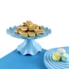 A light blue plastic cake stand holding several rectangular sandwich cookies on a blue surface.