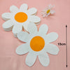 White daisy flower napkins with orange centers displayed on a pink background.