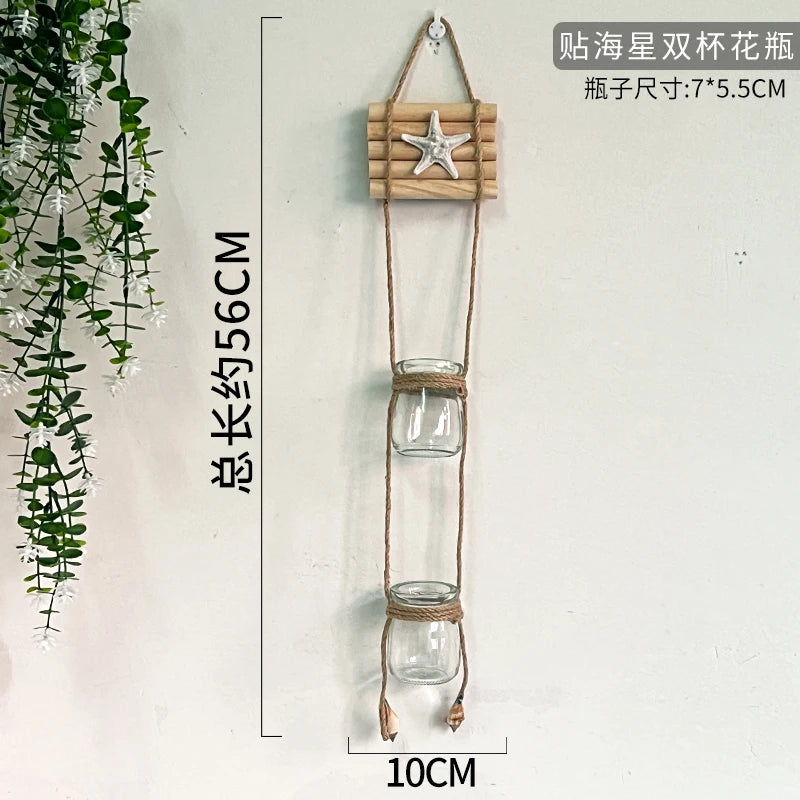 A decorative glass terrarium hanging by twine with a starfish charm, used for indoor plants.