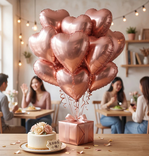 A bouquet of pink heart-shaped foil balloons is displayed on a wooden table with a cake and flowers.
