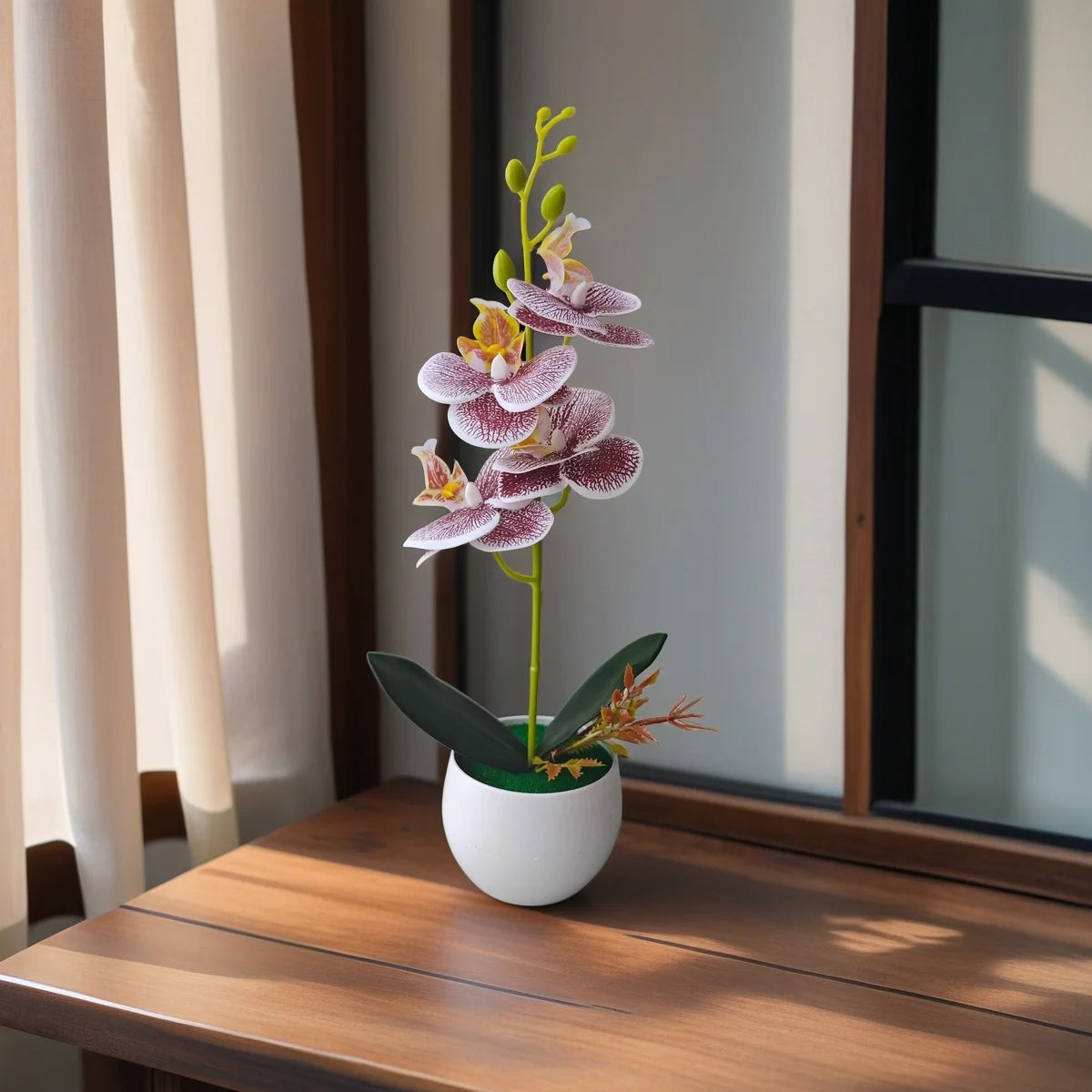 A realistic artificial orchid plant with purple and white flowers in a white pot sits on a wooden table.