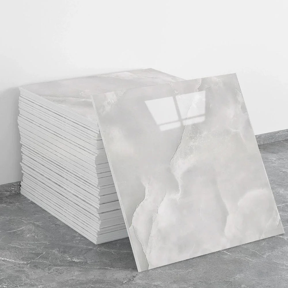 A stack of white self-adhesive marble tile stickers on a gray floor.
