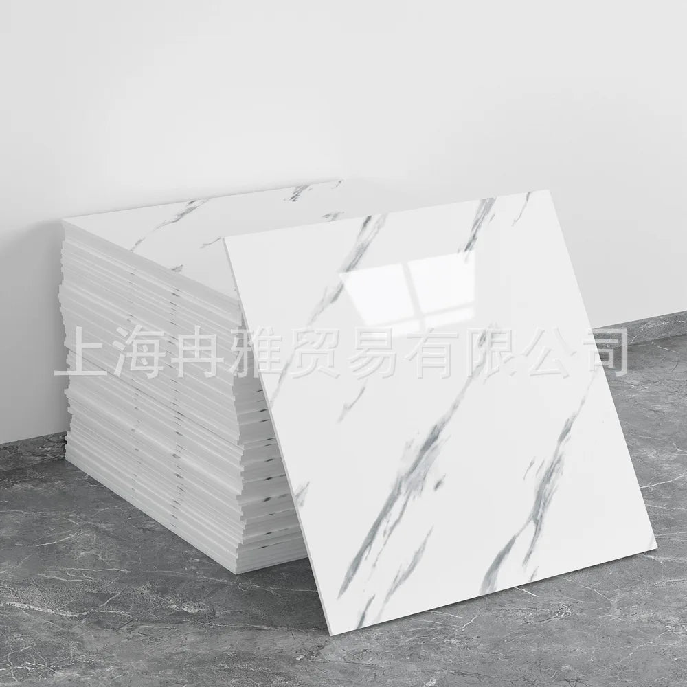 A stack of white faux marble peel-and-stick wall tiles with gray veining displayed on a gray floor.