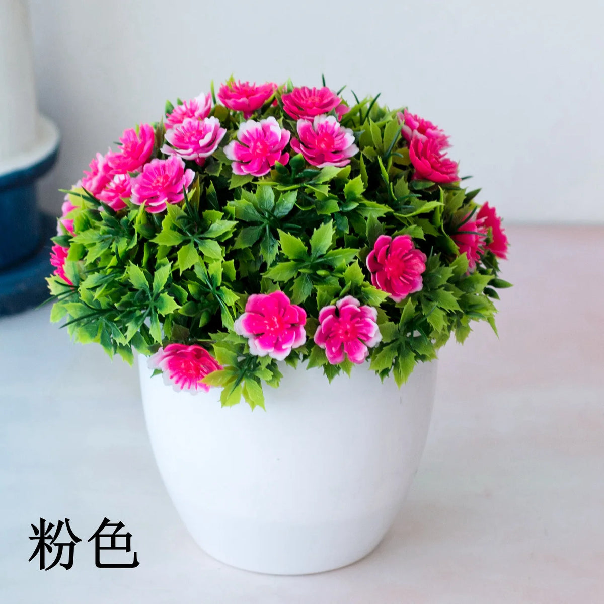 Un bouquet vibrant de fleurs artificielles roses et magenta dans un pot blanc.