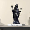 A dark resin statue of a goddess with a crown and mystical details standing on a book.