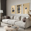 A modern living room features a light sofa, wooden coffee table, and framed art prints on the wall.