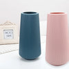 A set of three tall, ribbed ceramic flower vases in dusty blue, pink, and off-white tones.