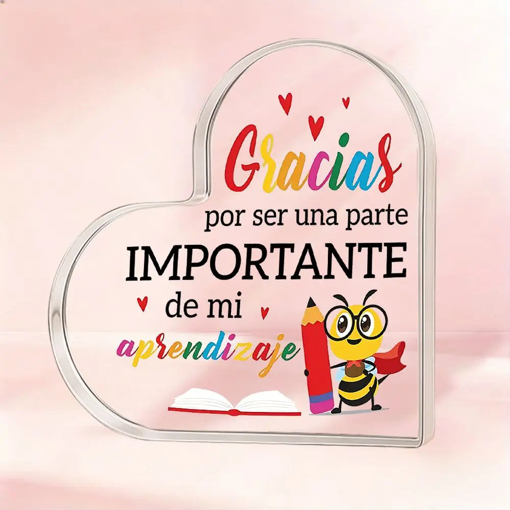 A clear acrylic heart plaque with the text Gracias por ser una parte importante de mi aprendizaje and a bee design.