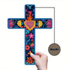A colorful floral Mexican cross wall art piece is being hung on a wooden nail.