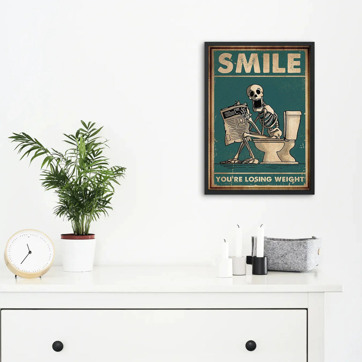 A framed canvas print featuring a skeleton man squatting on a toilet with the text You're losing weight.