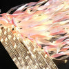 Golden LED glow wands with pink ribbons and bells creating a sparkling light effect