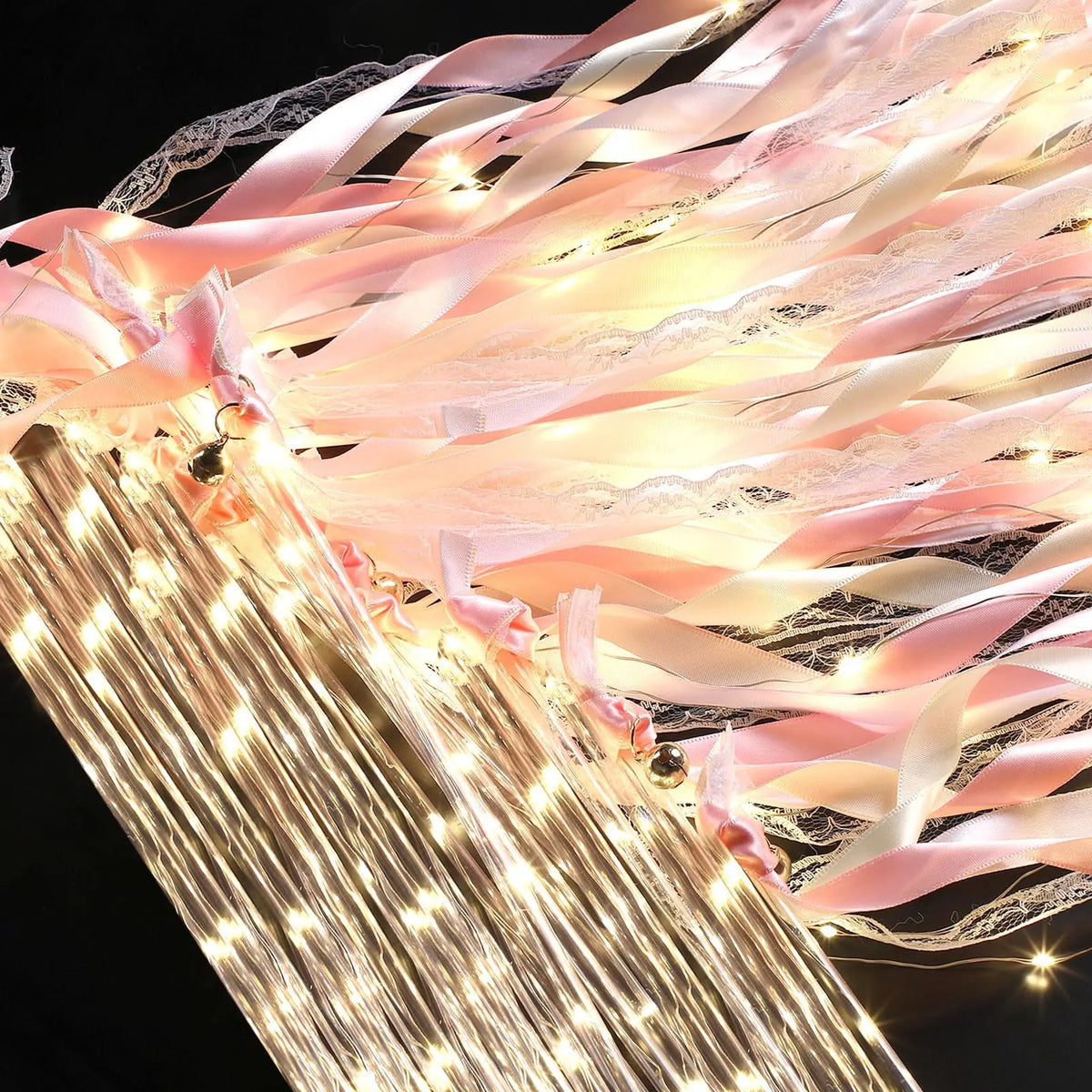 Golden LED glow wands with pink ribbons and bells creating a sparkling light effect